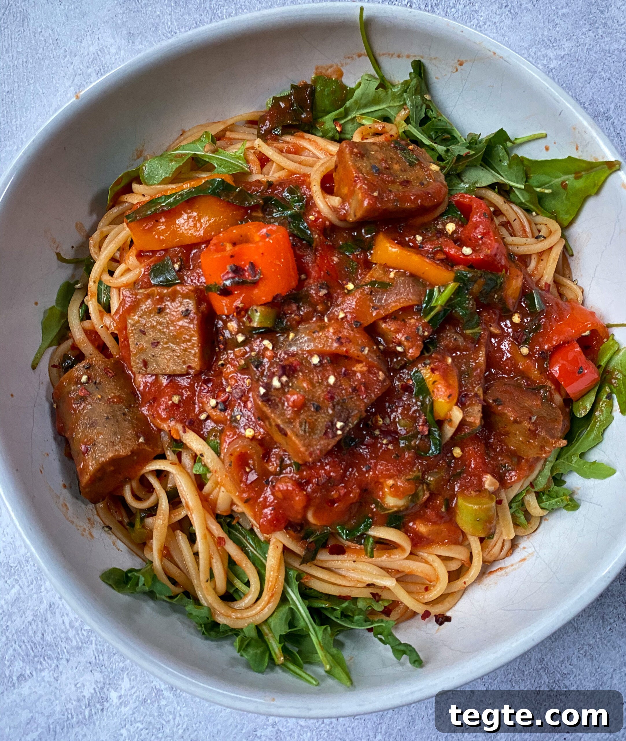 26 Cozy Vegan Dinners to Warm Your Winter Nights 21 overhead view of a white bowl holding vegan sausage pasta with veggies and plant based sausage.