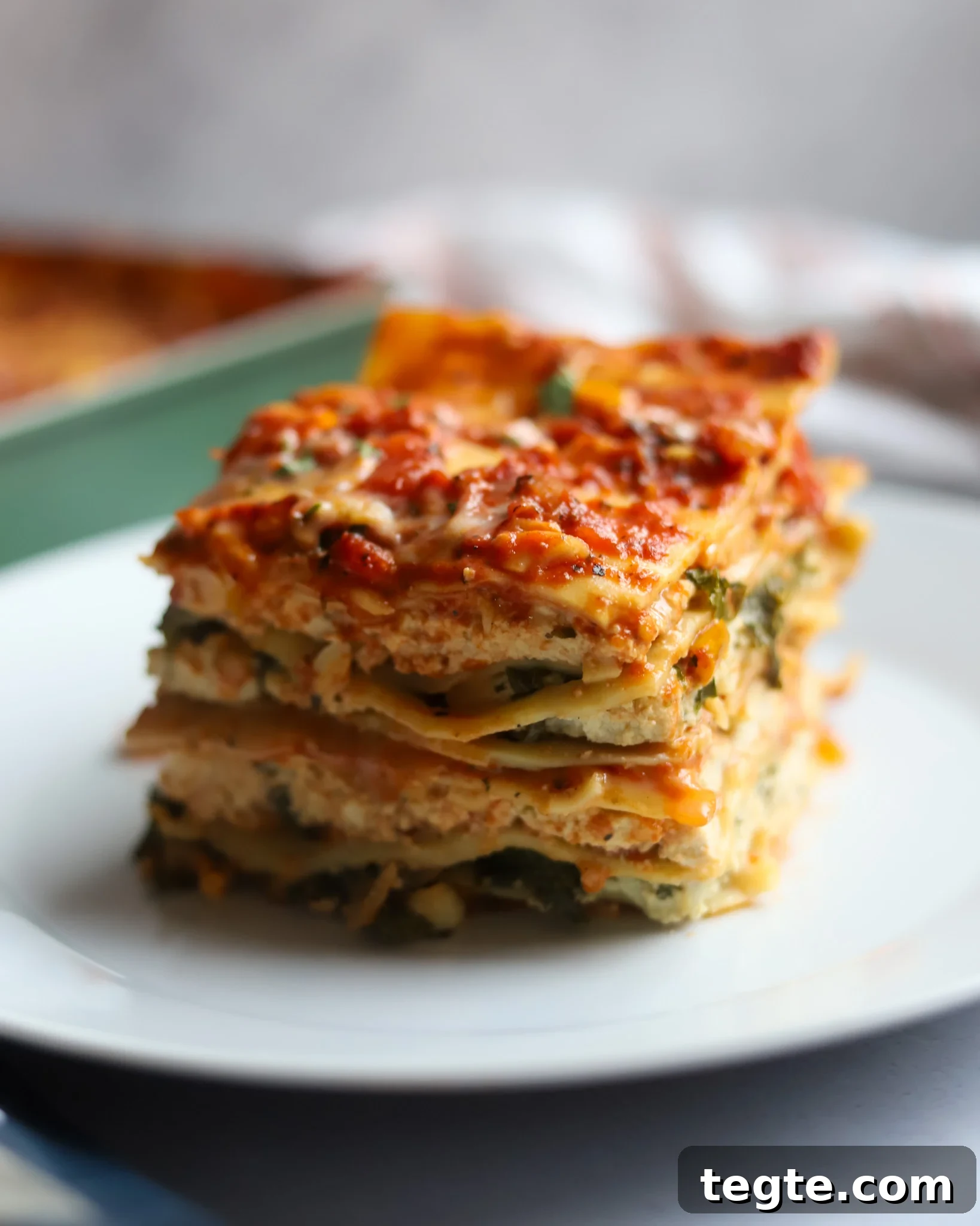 26 Cozy Vegan Dinners to Warm Your Winter Nights 23 cheesy vegan lasagna with tofu ricotta on a white plate.