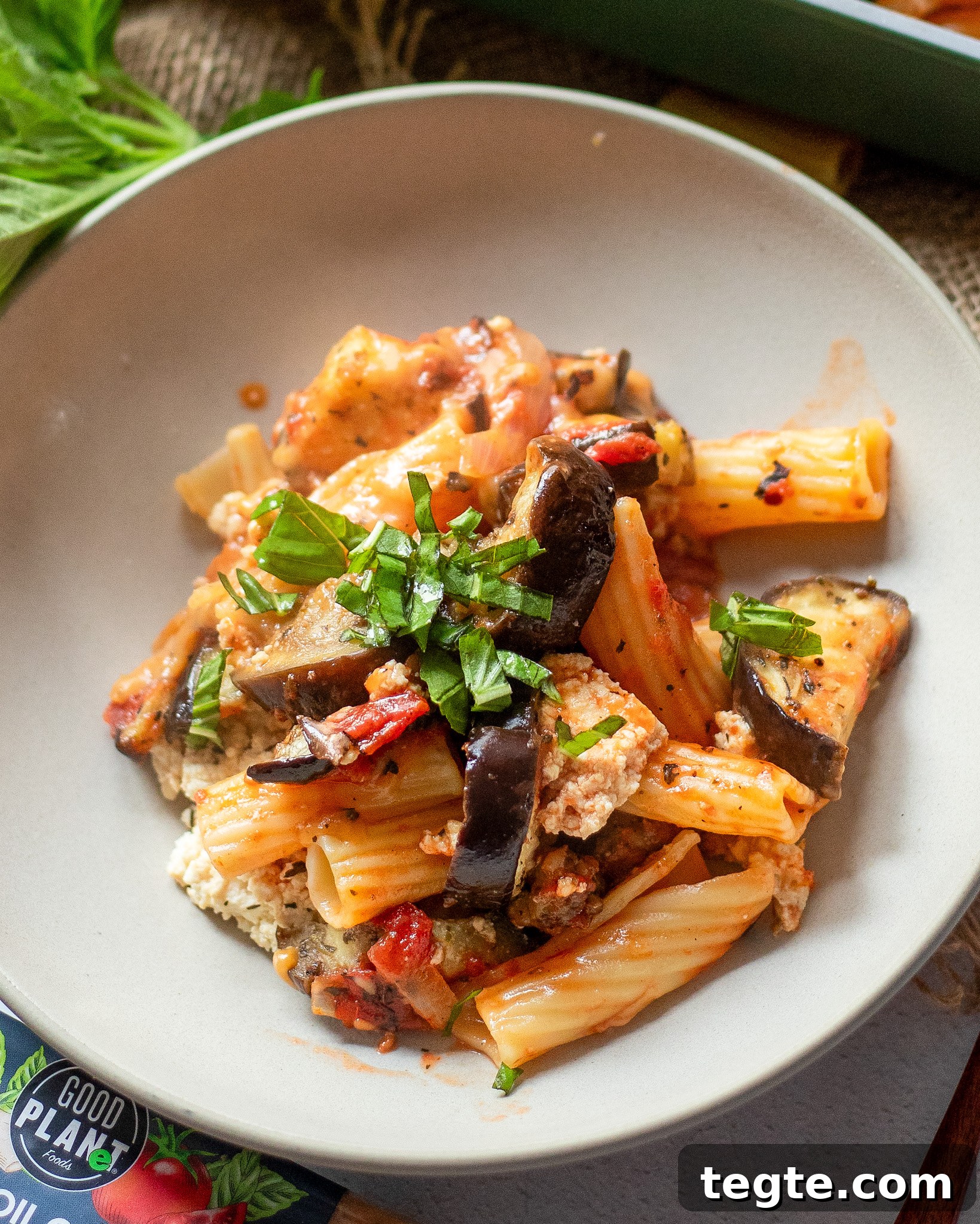26 Cozy Vegan Dinners to Warm Your Winter Nights 25 close up view of a white plate with vegan eggplant pasta made with roasted pasta, tomato sauce, and vegan cheese.