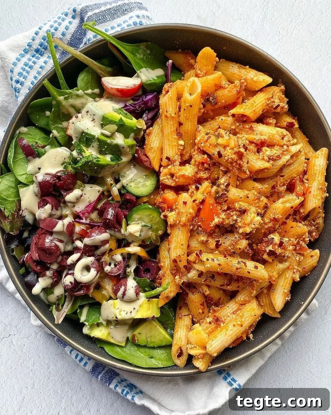 26 Cozy Vegan Dinners to Warm Your Winter Nights 28 overhead view of a dinner plate with vegan baked ziti next to a green salad.