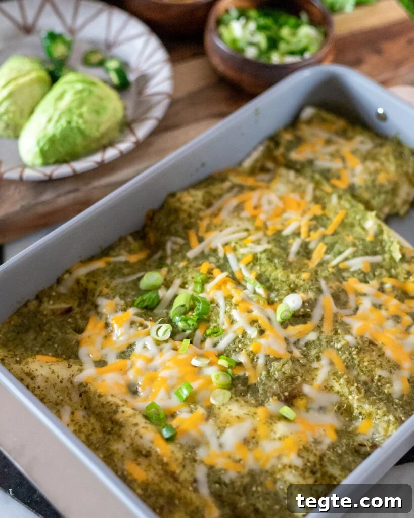 26 Cozy Vegan Dinners to Warm Your Winter Nights 10 Vegan Enchiladas Verdes in a white casserole dish with melted cheese on top.
