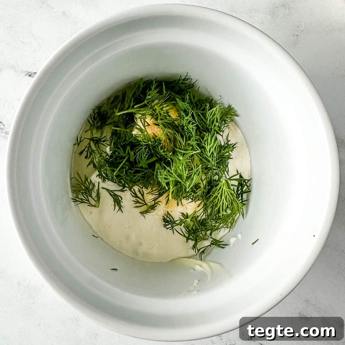 Creamy Dill Sauce for Fish, Salmon, and Vegetables 4 mayonnaise, cream cheese, garlic powder, lemon juice, and fresh dill in a white ramekin.