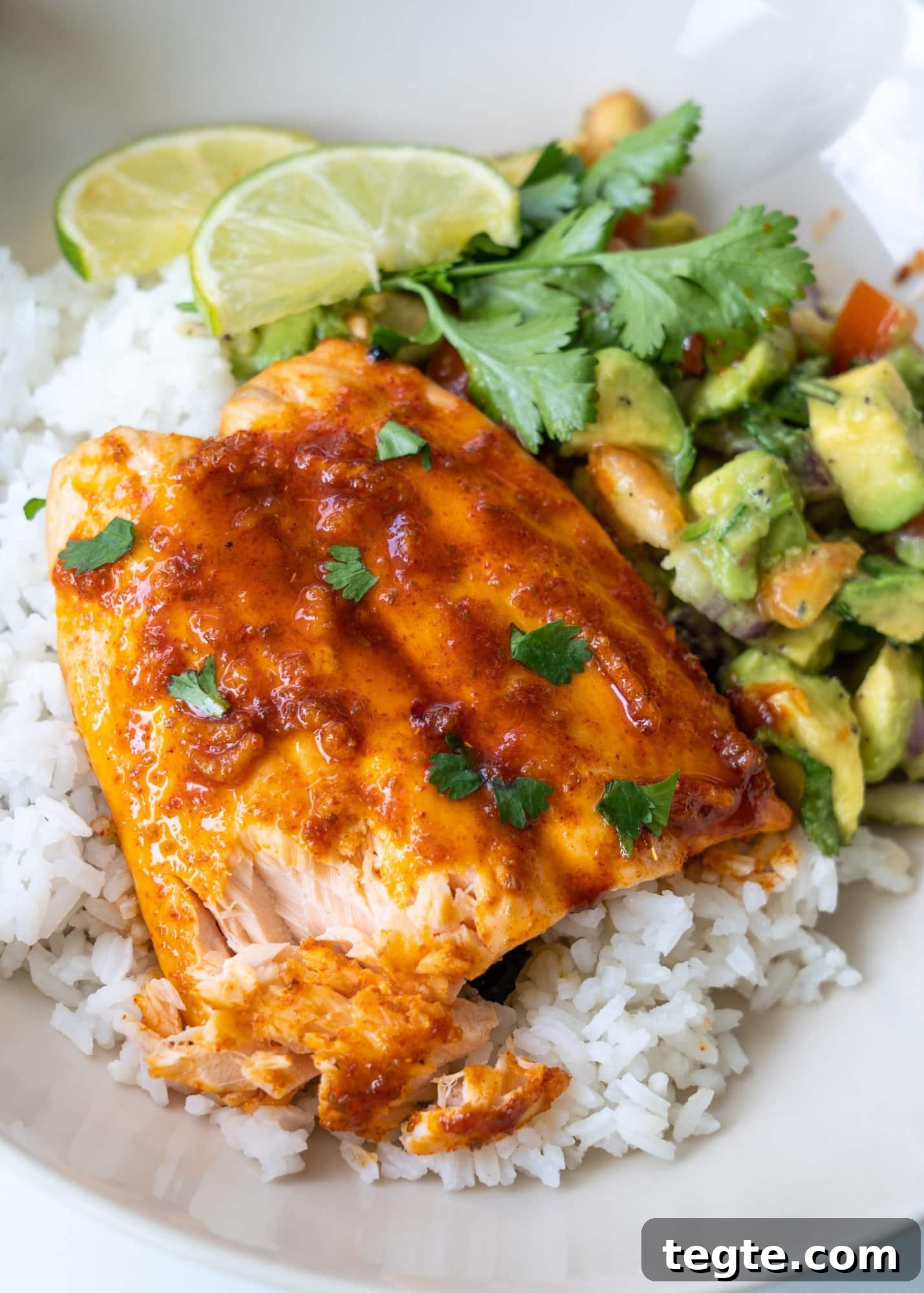 Chili-Lime Marinated Baked Salmon Recipe 4 Shown tender and flaky baked salmon served with rice, avocado salad, lime slice and chopped celery.
