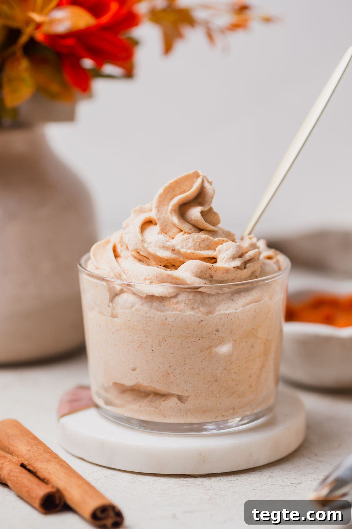 Pumpkin-Spiced Whipped Cream Recipe for Fall Desserts 2 pumpkin whipped cream with a spoon in a jar.