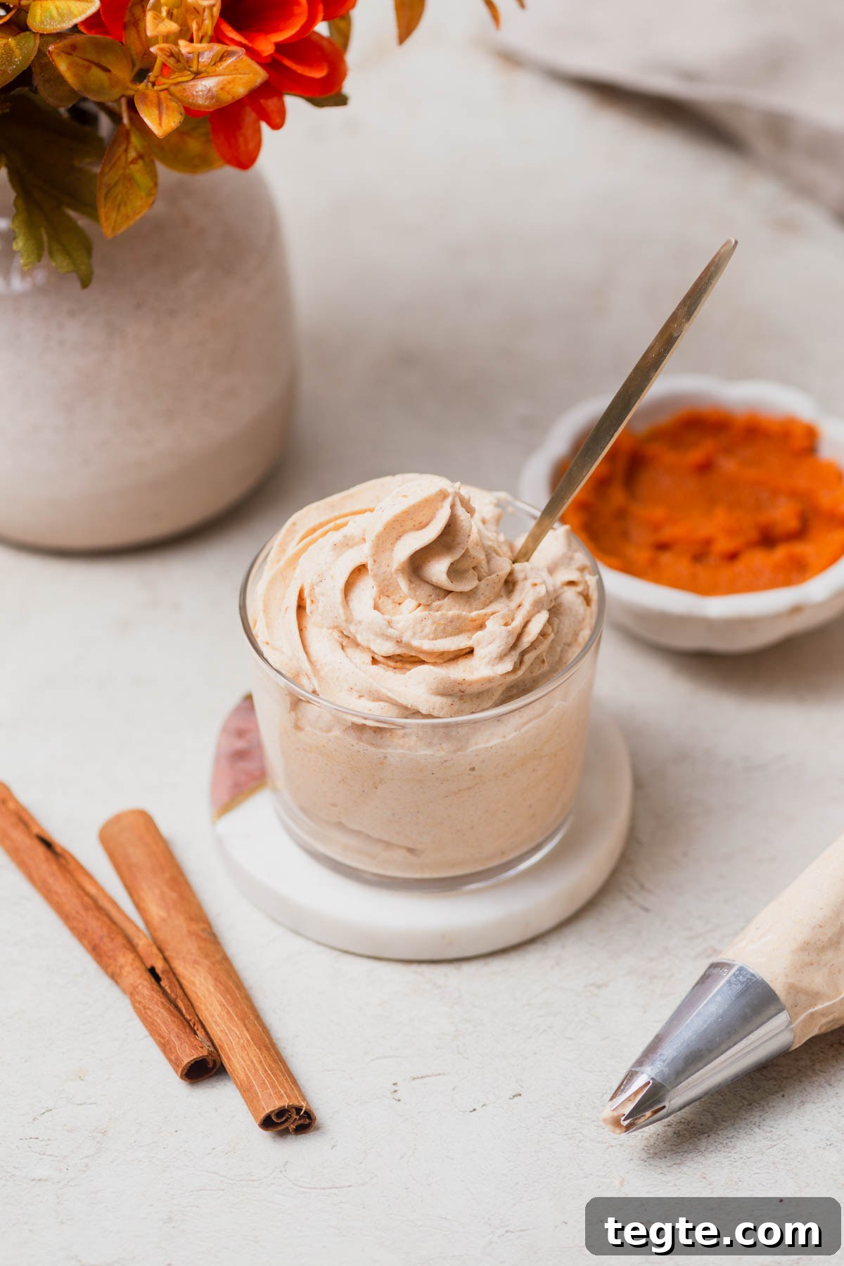 Pumpkin-Spiced Whipped Cream Recipe for Fall Desserts 8 pumpkin spice whipped cream with cinnamon sticks and pumpkin puree on the side.