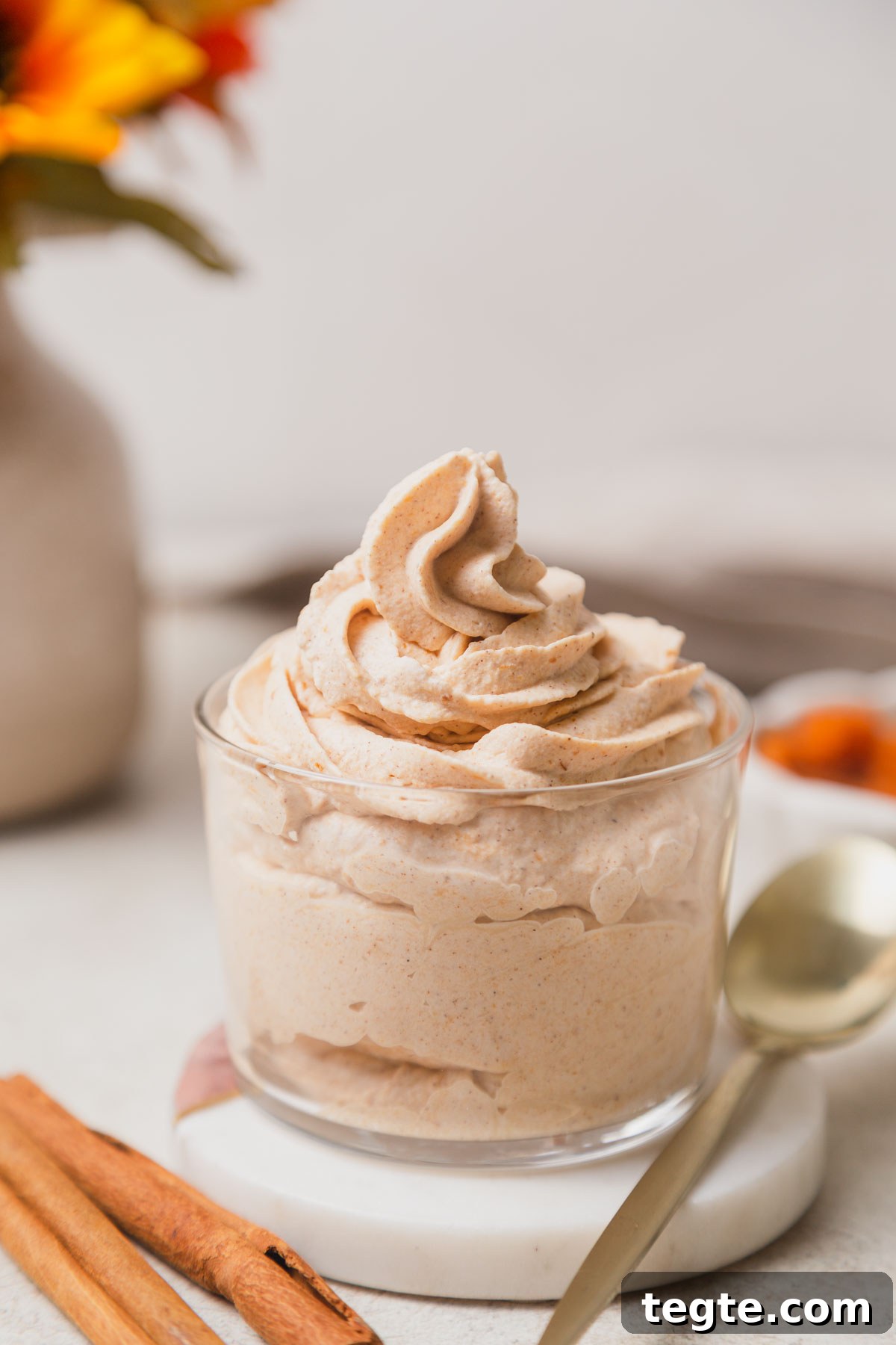 Pumpkin-Spiced Whipped Cream Recipe for Fall Desserts 9 pumpkin spice whipped cream topping in a jar with a spoon.