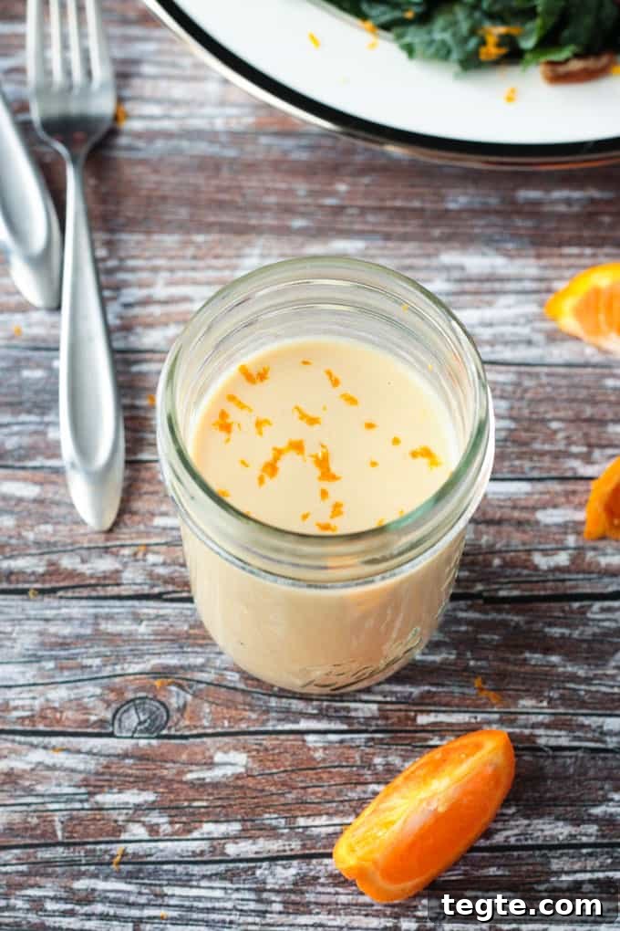 Citrus Tahini Dressing - this creamy, oil-free dressing is the perfect drizzle for all of your leafy greens. Fresh squeezed orange juice for sweetness and apple cider vinegar for tang combine with the creamy tahini for the perfect flavor balance. Overhead view of a jar of dressing sprinkled with orange zest.