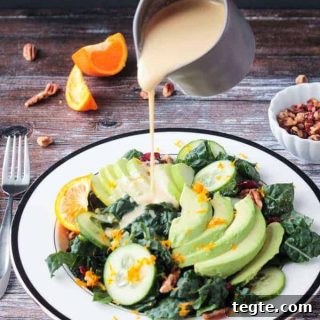 Bright Citrus Tahini Dressing Recipe for Salads & Bowls 2 Orange Tahini Dressing being poured onto a lacinato kale salad.