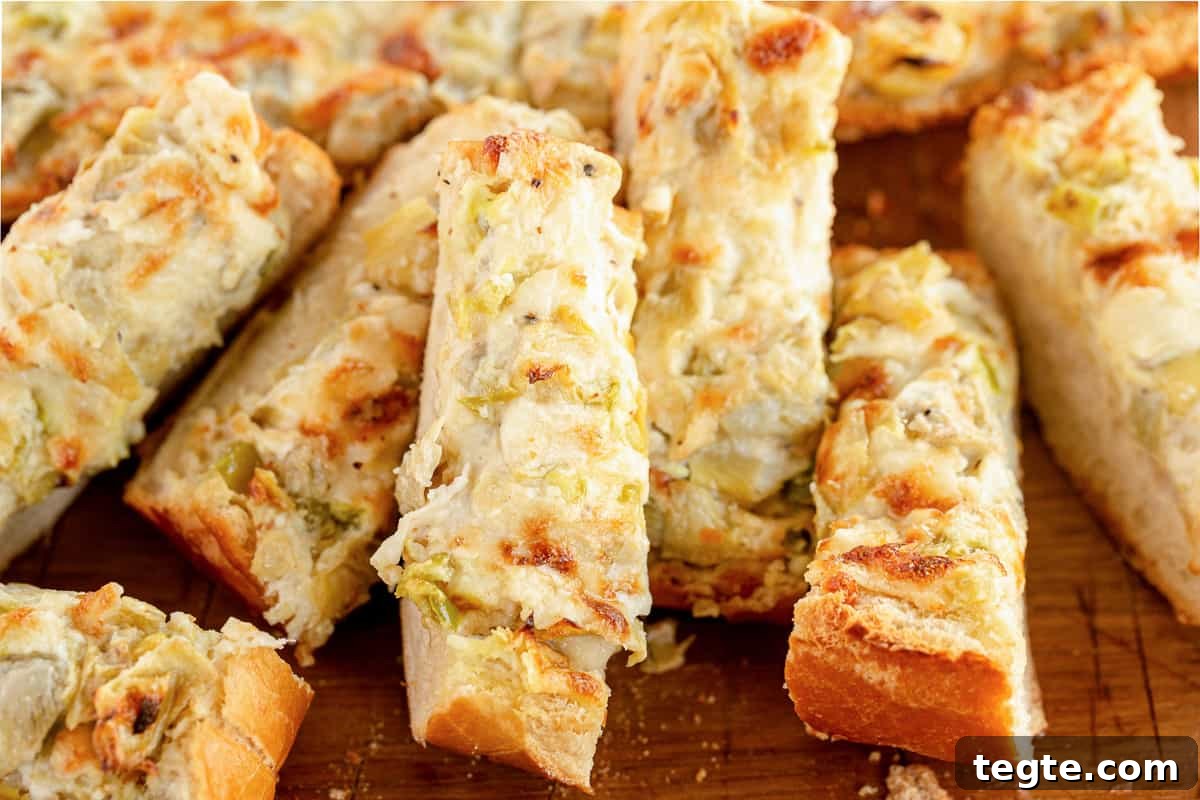 Cheesy Artichoke Pull-Apart Bread for Parties and Snacks 5 Sliced artichoke bread on a cutting board.
