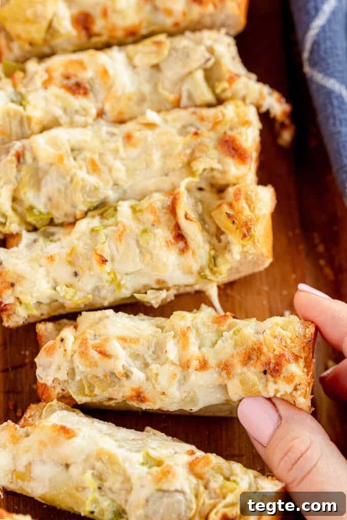 Cheesy Artichoke Pull-Apart Bread for Parties and Snacks 9 A hand taking a piece of Cheesy Artichoke Bread.