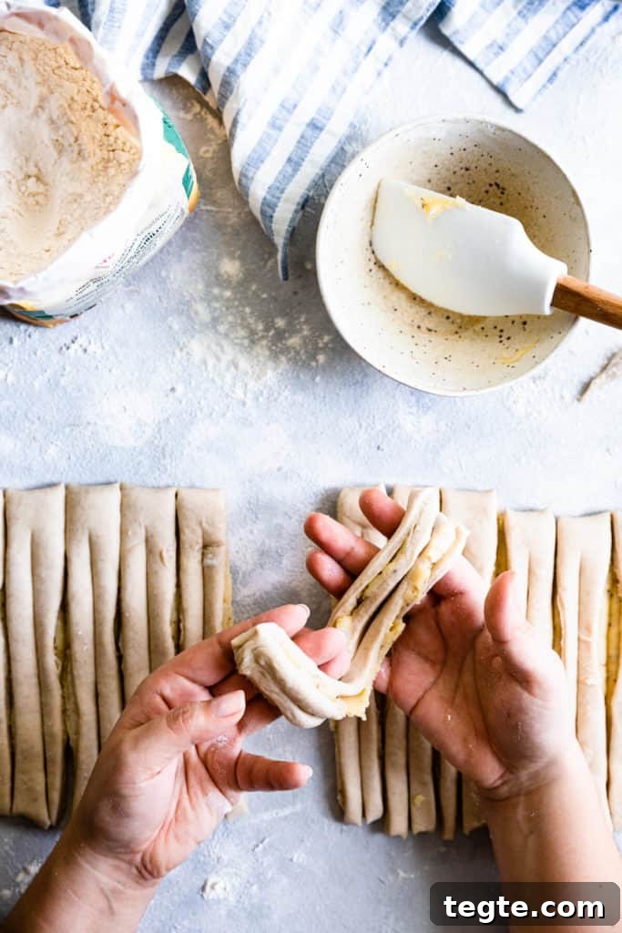 Authentic Swedish Cardamom Buns (Kardemummabullar) Recipe 11 top view of a person holding a strip of dough