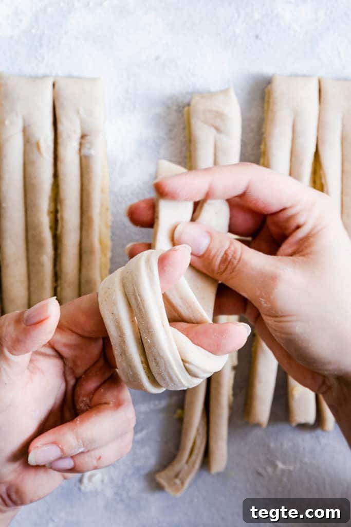 Authentic Swedish Cardamom Buns (Kardemummabullar) Recipe 14 close up of a person's hands shaping the dough into knot
