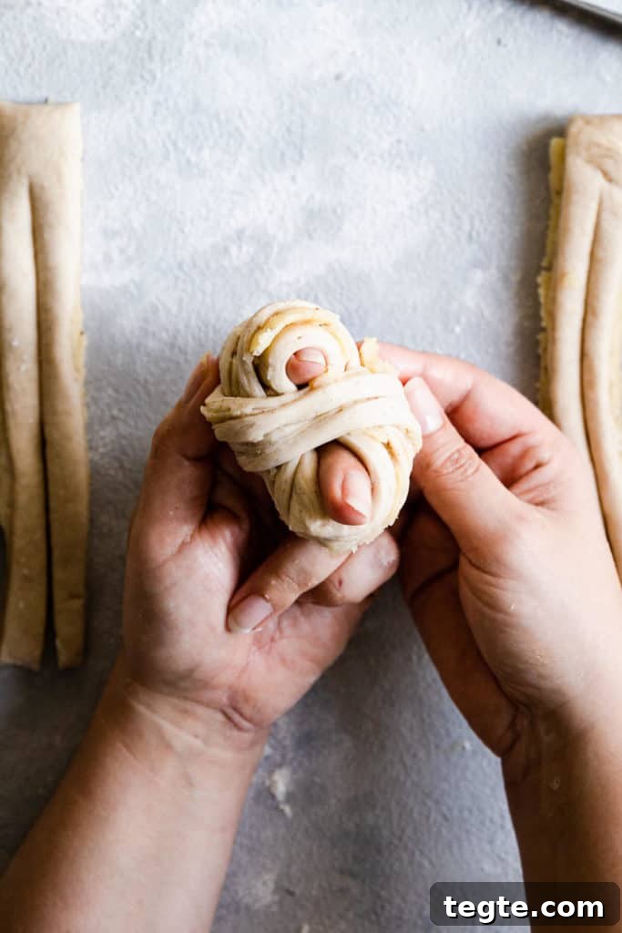 Authentic Swedish Cardamom Buns (Kardemummabullar) Recipe 16 top view of hands shaping the dough into knot