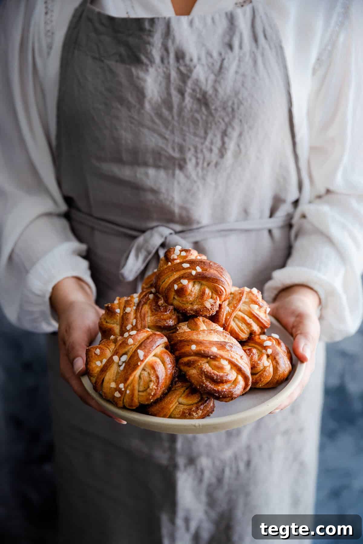 Authentic Swedish Cardamom Buns (Kardemummabullar) Recipe 3 straight ahead shot of a person holding a plate with buns