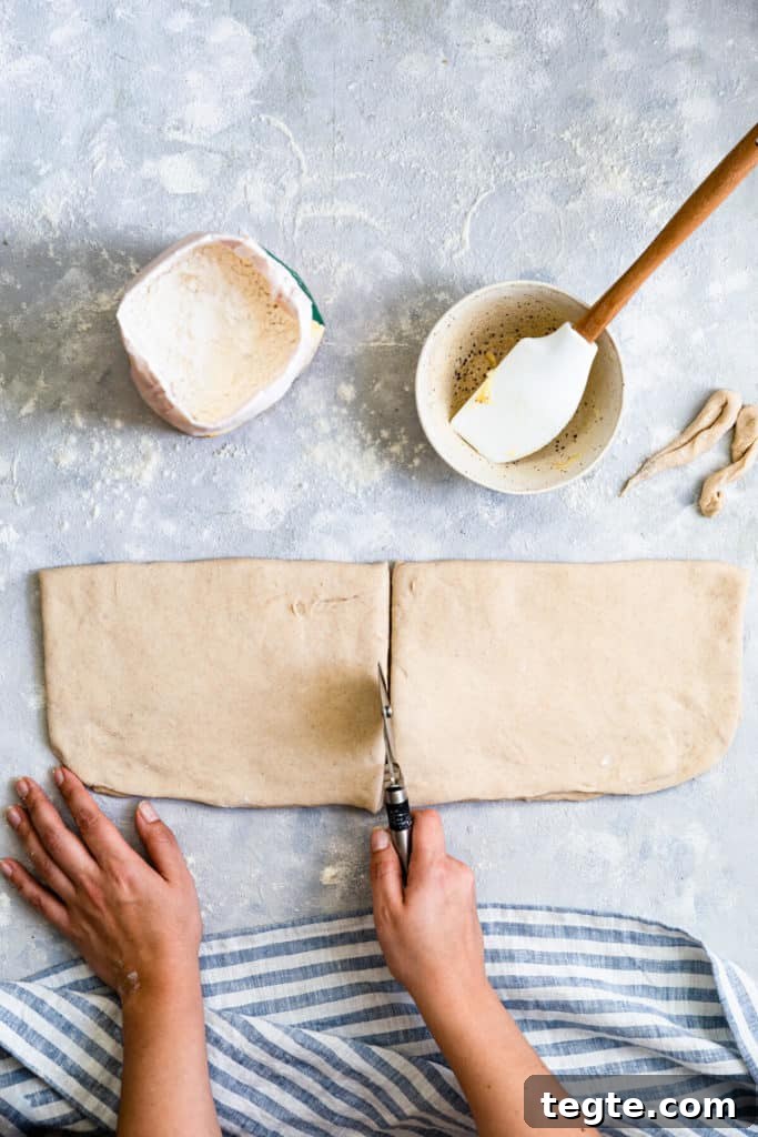 Authentic Swedish Cardamom Buns (Kardemummabullar) Recipe 8 overhead shot of a person using a pizza cutter to slice the dough