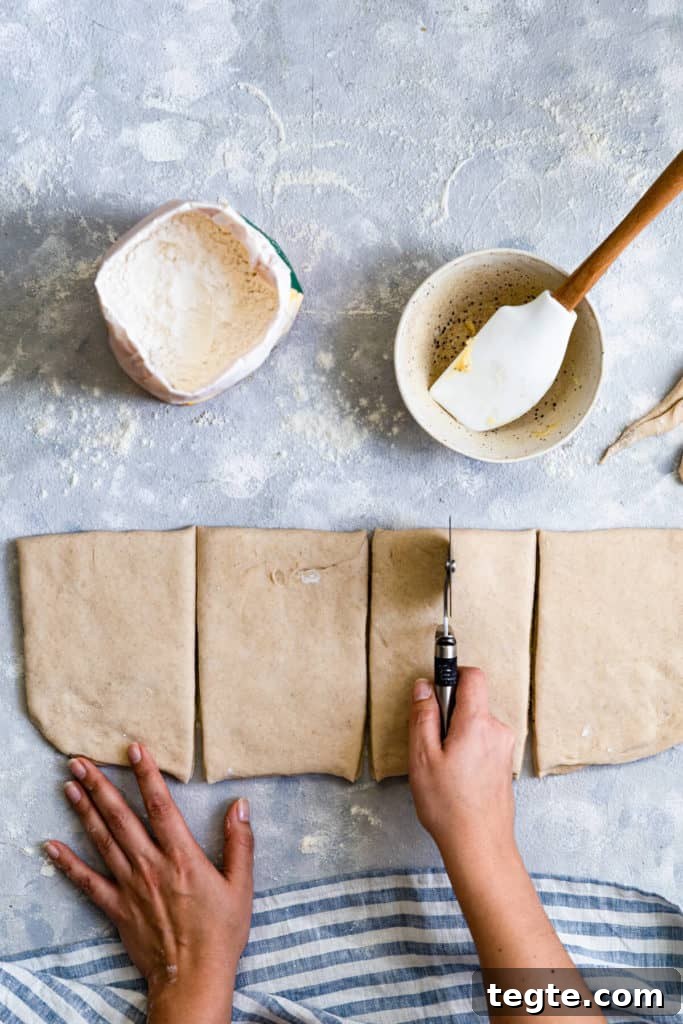Authentic Swedish Cardamom Buns (Kardemummabullar) Recipe 9 top view of a person slicing the dough with pizza cutter