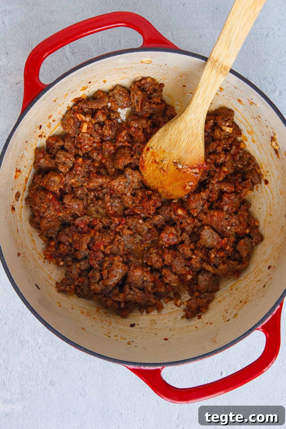 Tomato paste mixed in with cooked Italian sausage