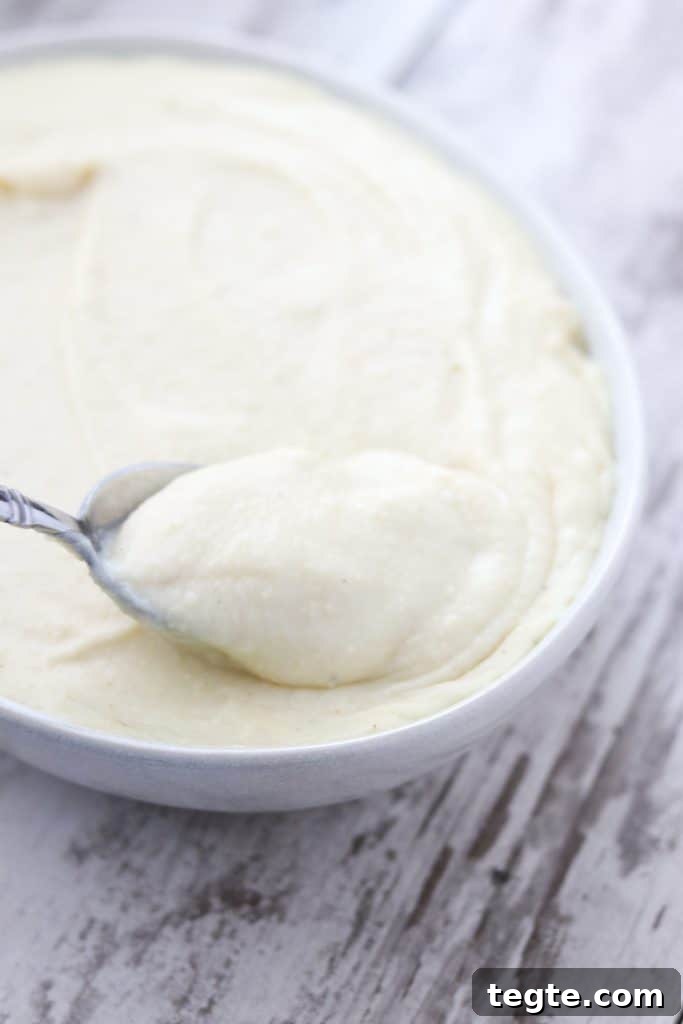 A bowl of potato and celery root puree with a spoon on a wooden surface