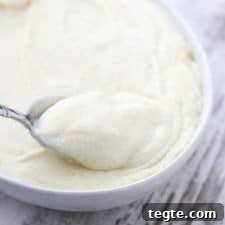 A bowl of potato and celery root puree with a spoon on a wooden surface