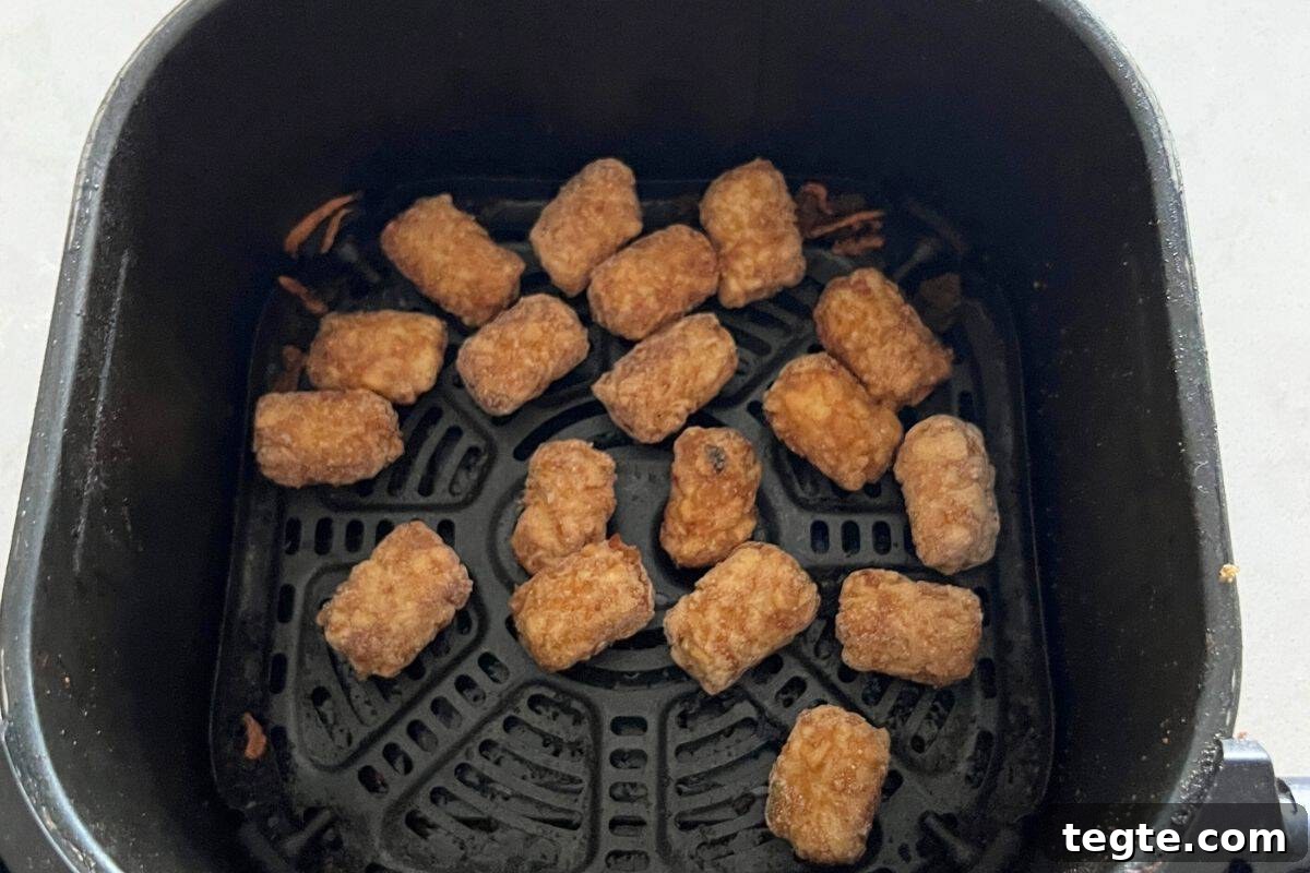 Hearty Country Breakfast Bowl Recipe for Morning Energy 3 Tator tots in air fryer basket.