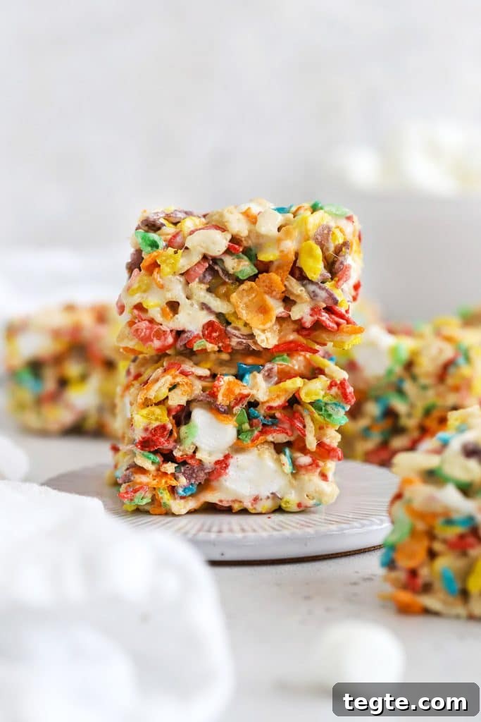 Gluten-Free Scotcheroos Recipe: Chewy No-Bake Chocolate Peanut Bars 11 two fruity pebble rice krispies treats stacked on a white dessert plate