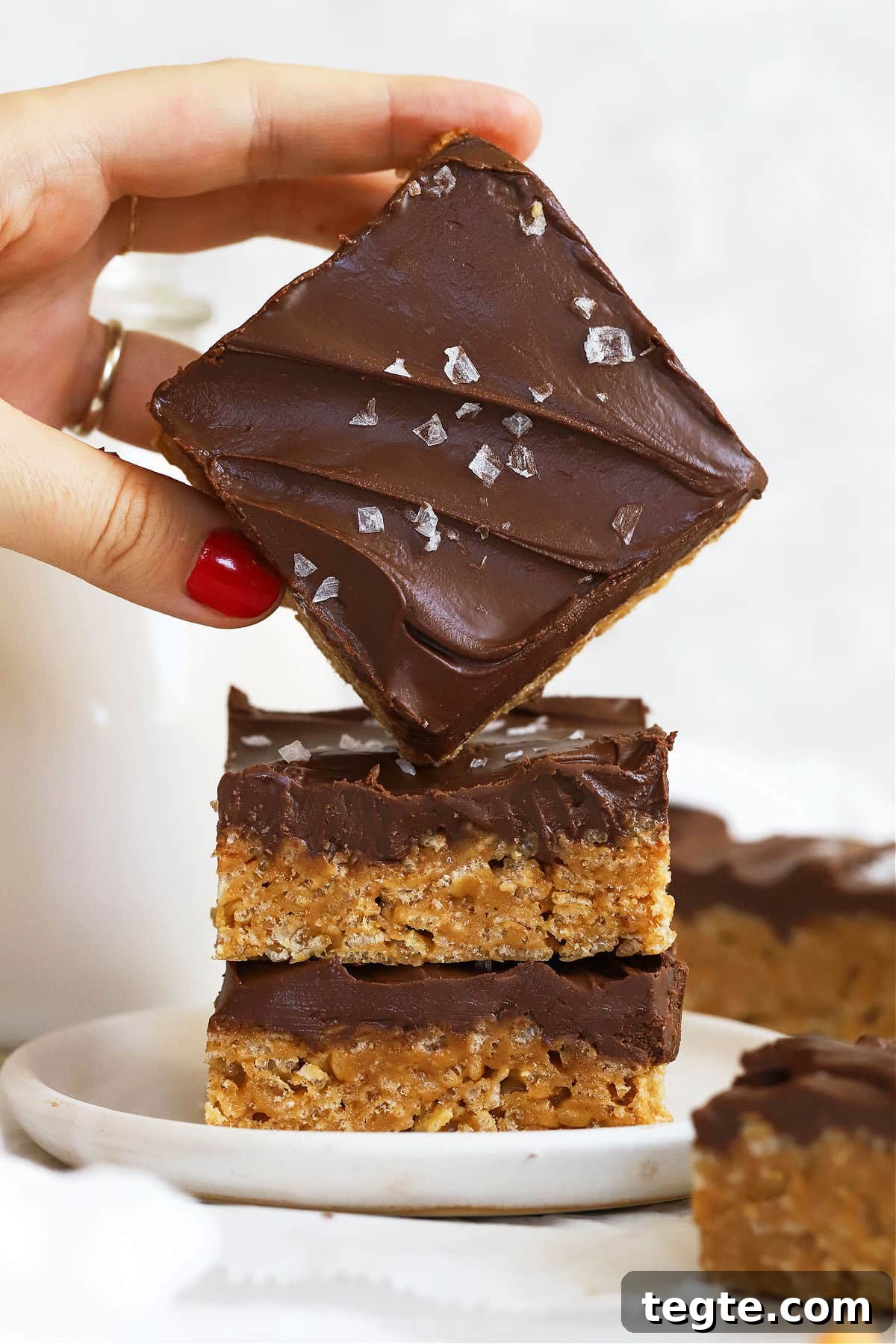 Gluten-Free Scotcheroos Recipe: Chewy No-Bake Chocolate Peanut Bars 7 stacking gluten-free scotcheroos on a white dessert plate