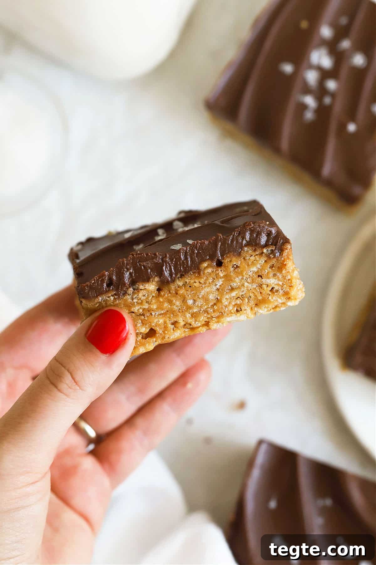 Gluten-Free Scotcheroos Recipe: Chewy No-Bake Chocolate Peanut Bars 8 hand holding up a gluten-free scotcheroo to show the texture