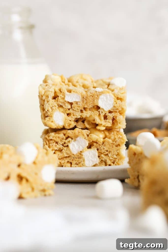 Gluten-Free Scotcheroos Recipe: Chewy No-Bake Chocolate Peanut Bars 9 gluten-free peanut butter rice krispie treats stacked on a white plate