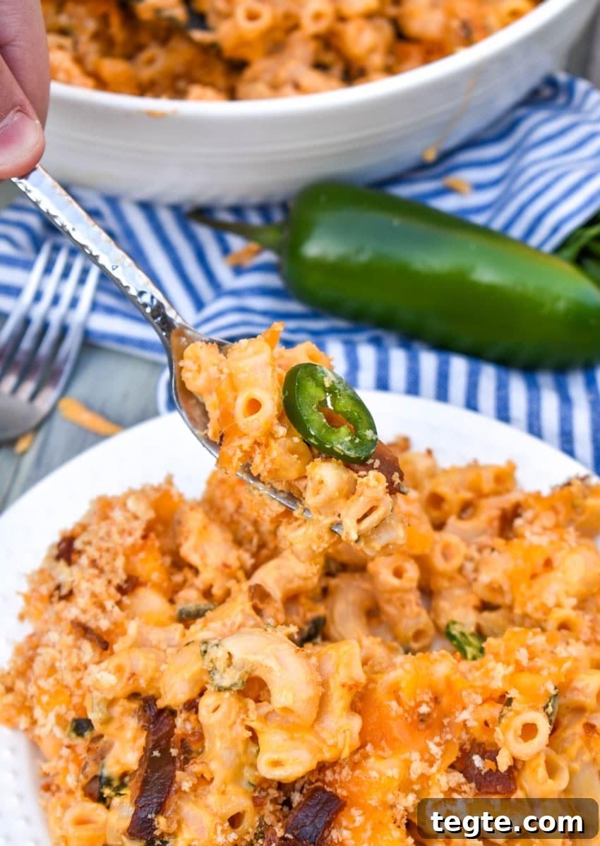 a silver fork lifting up a bite of jalapeno popper mac and cheese
