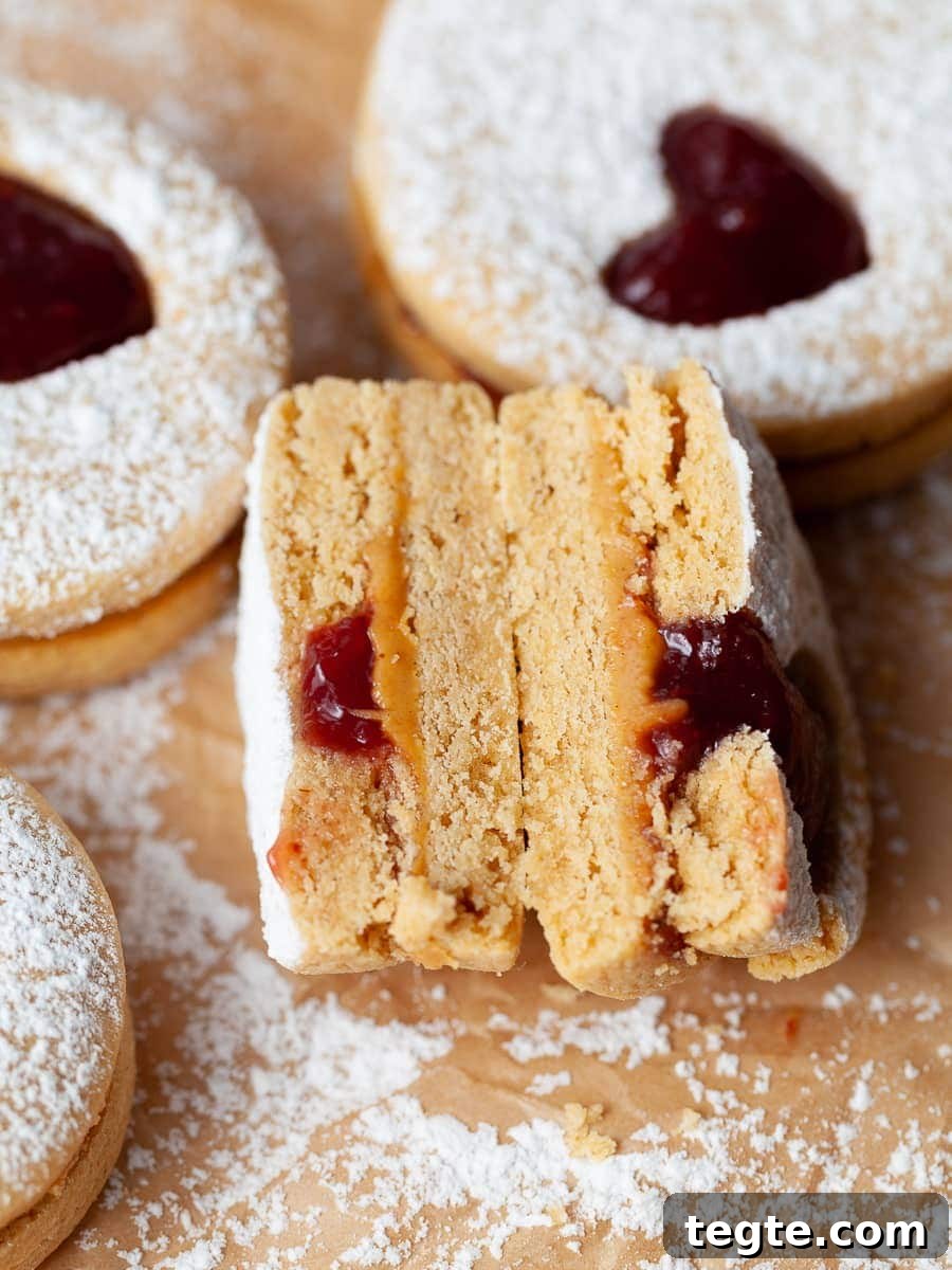 Gluten-Free Peanut Butter & Jelly Cookies Recipe 10 a broken in half peanut butter and jam sandwich cookie