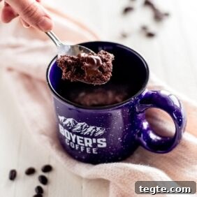 Microwave Double Chocolate Chip Mug Cookie Recipe 6 hand holding spoon with double chocolate chip cookie. Blue mug with cookie inside