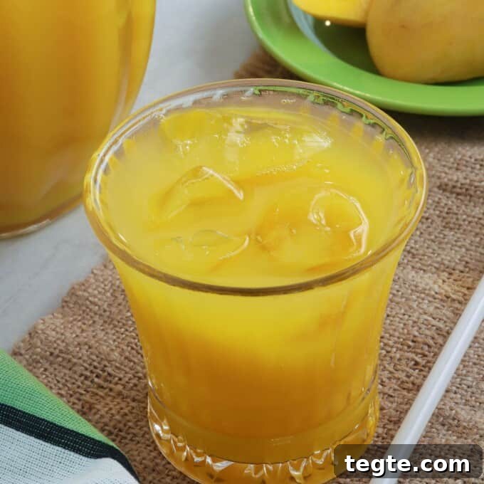 Homemade Mango Nectar Recipe: Smooth, Fresh Mango Drink 10 mango juice in a clear glass with pitcher on the side