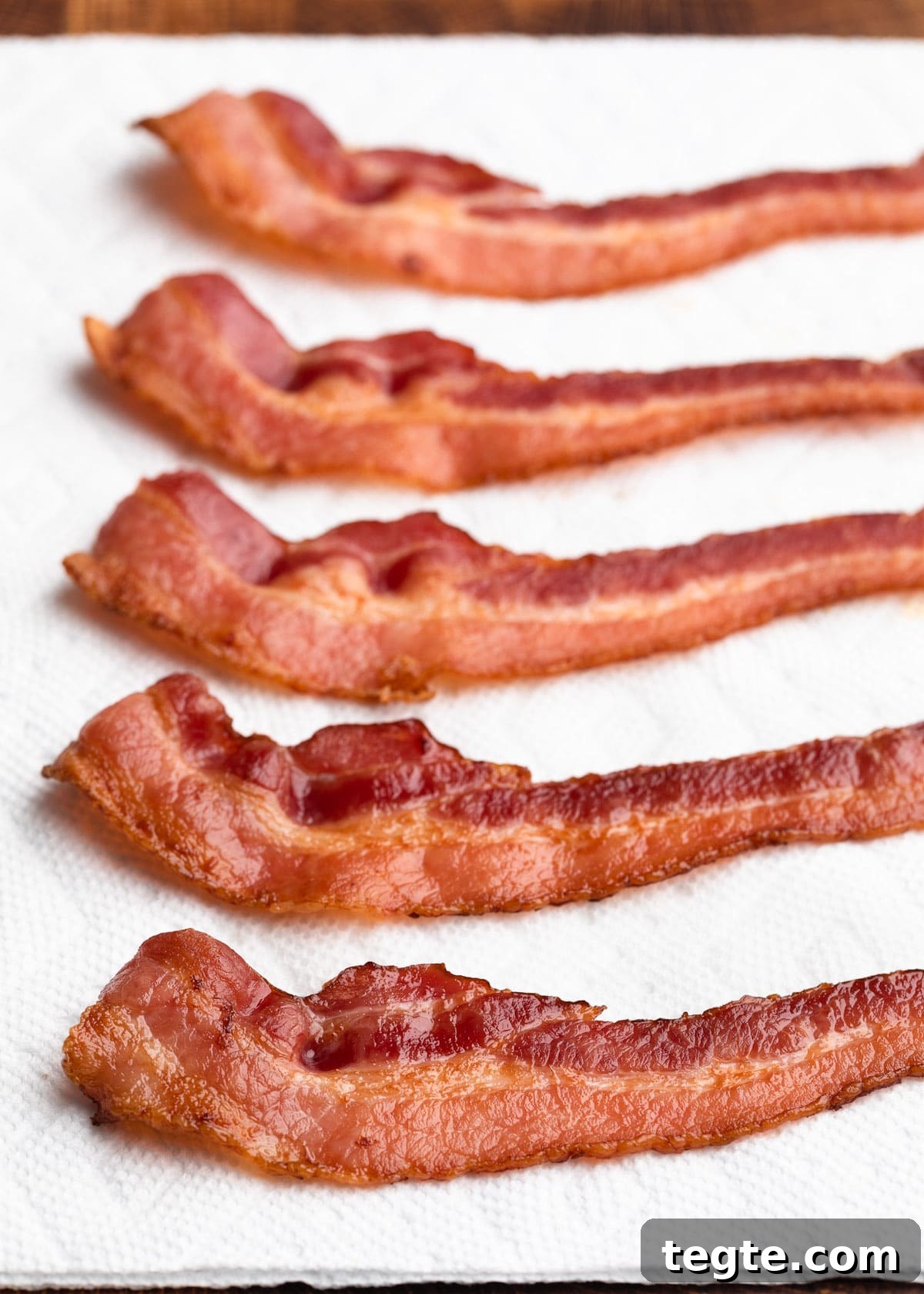 baked bacon strips draining on paper towels
