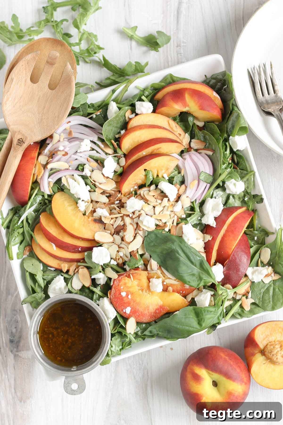 Peach and goat cheese salad with a side of balsamic vinaigrette and sliced peaches on the side.