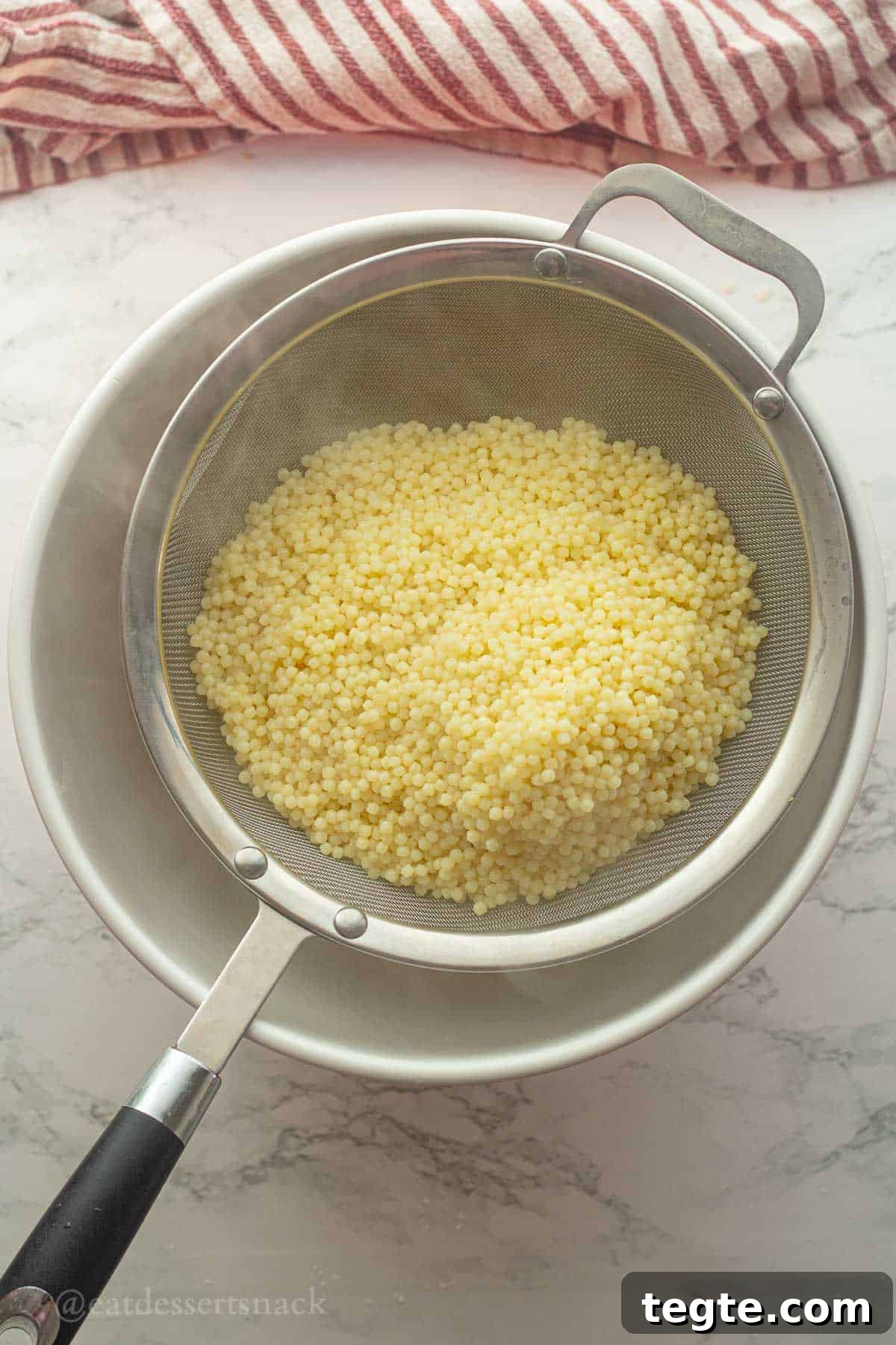 Acini de pepe noodles in strainer.
