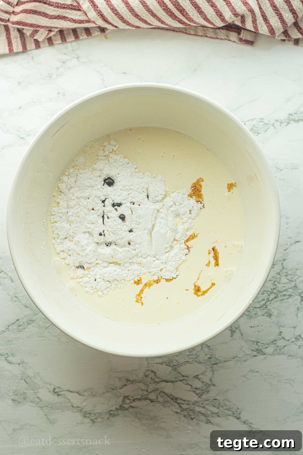 Powdered sugar and vanilla in bowl of cream.