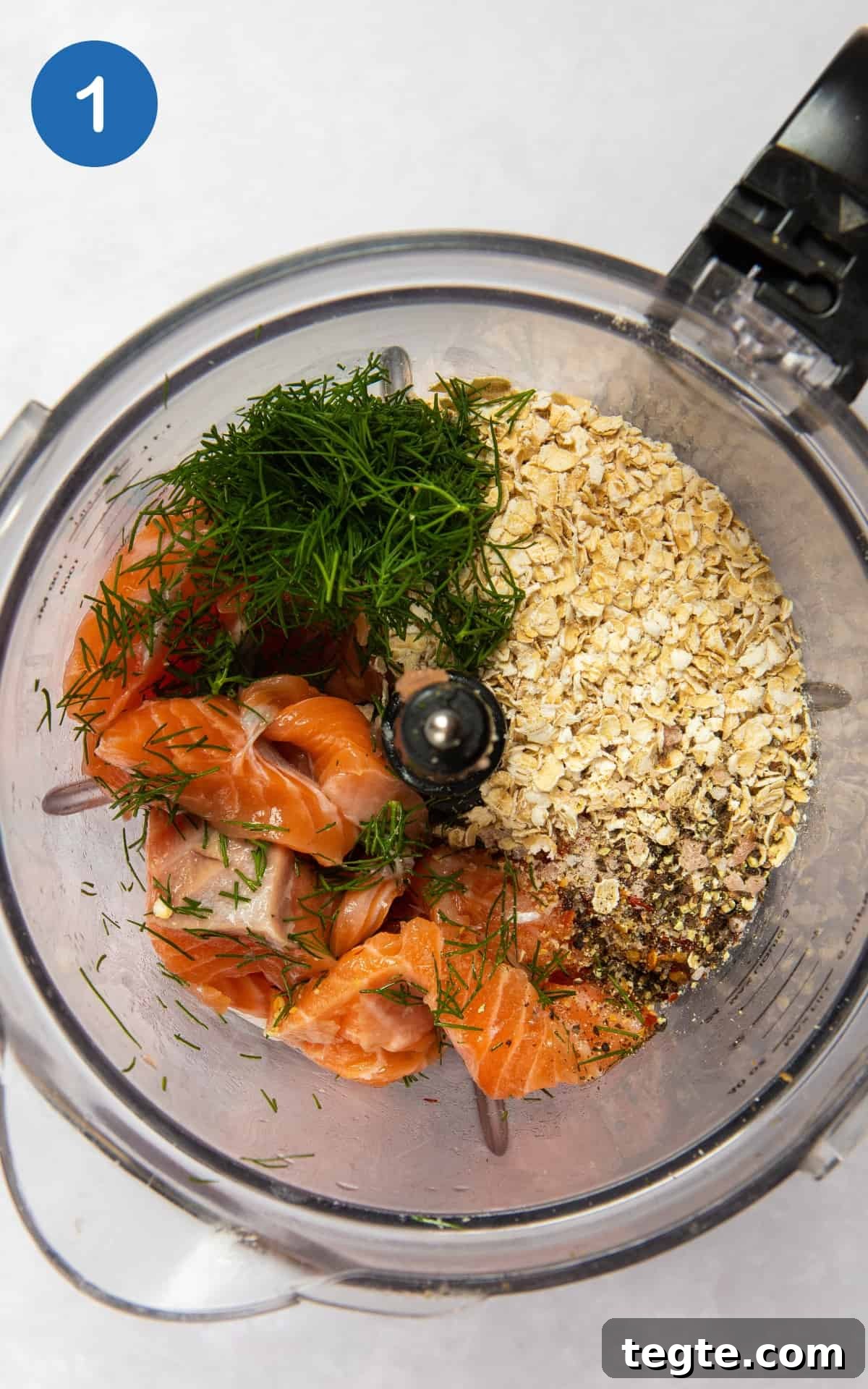 Crispy Salmon Burgers with Lemon-Dill Sauce 4 ingredients to make salmon burgers in food processor on white surface.