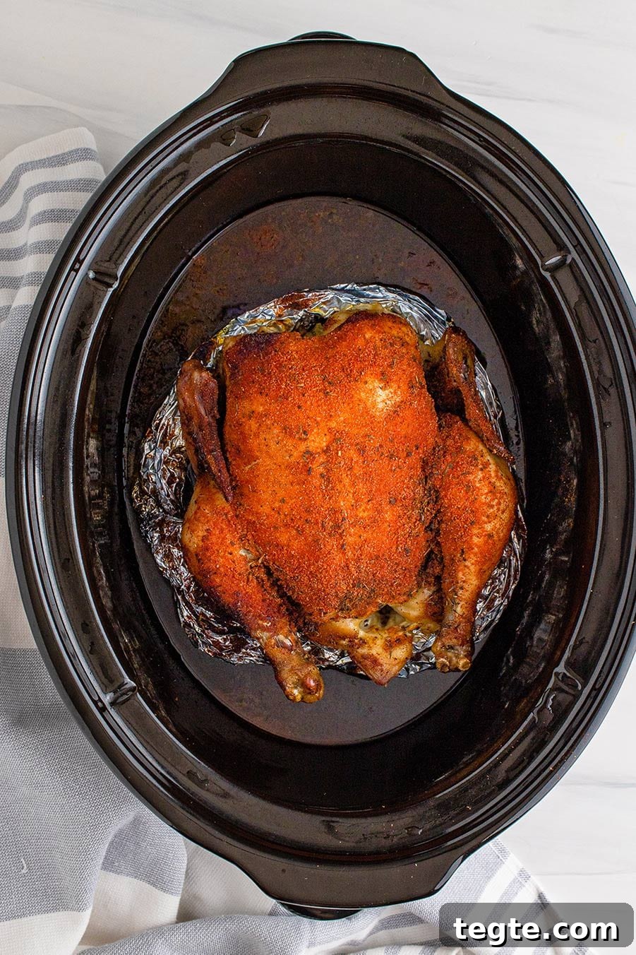 slow cooker whole chicken on top of aluminum foil.