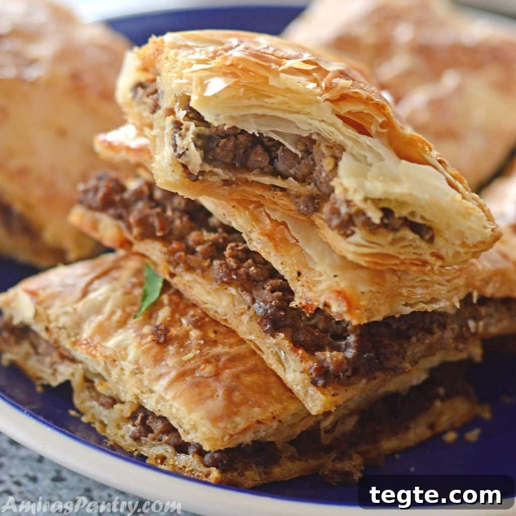 Egyptian Phyllo Meat Pie (Goulash) Recipe 2 Phyllo squares cut and stacked on top of eachother on a blue plate with a white rim.
