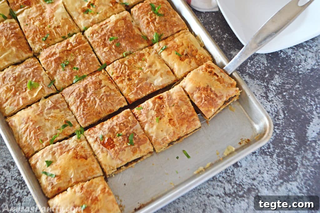 Egyptian Phyllo Meat Pie (Goulash) Recipe 4 A baking sheet with phyllo squares cut side by side and placed on a dark grey table.