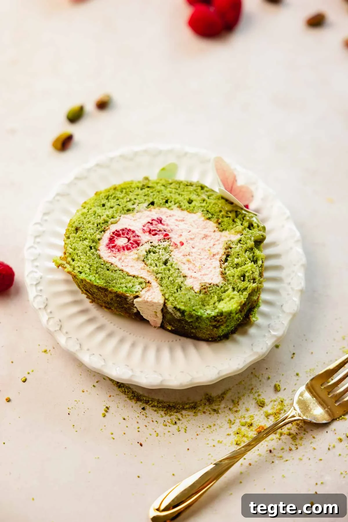 Raspberry and Pistachio Cake Roll Recipe for Spring Gatherings 19 slice of pistachio roll cake with raspberry filling on small white plate