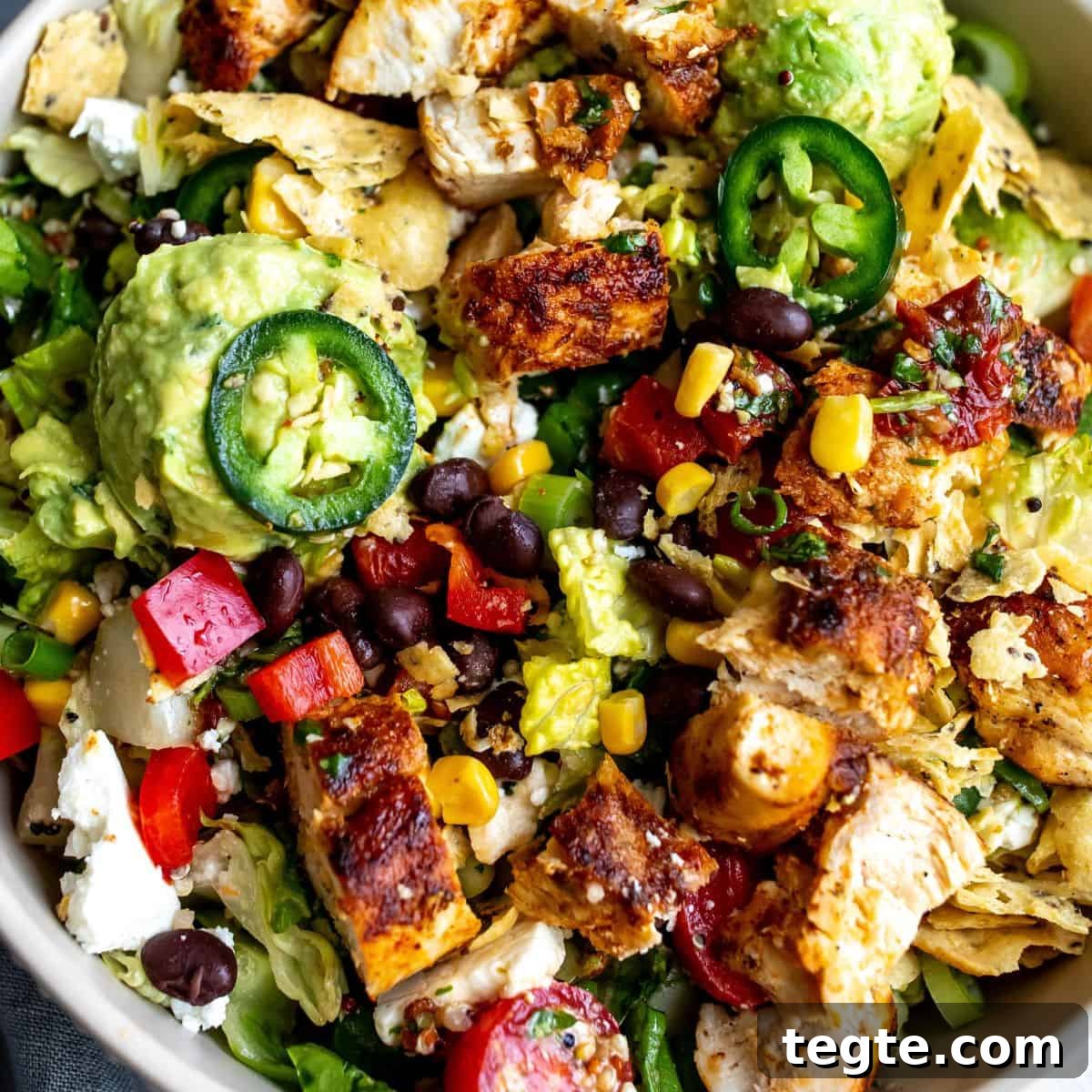 White bowl with salad up close with juicy seasoned chicken.