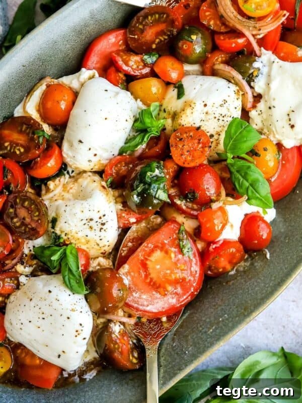Green serving dish with tomatoes, burrata and basil.