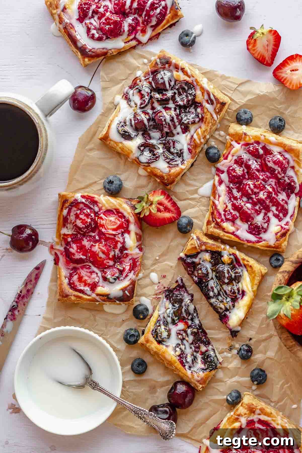 Fruit and Cream Cheese Danish with Flaky Puff Pastry 2 Various fruit and cheese danishes on a table with coffee nearby.