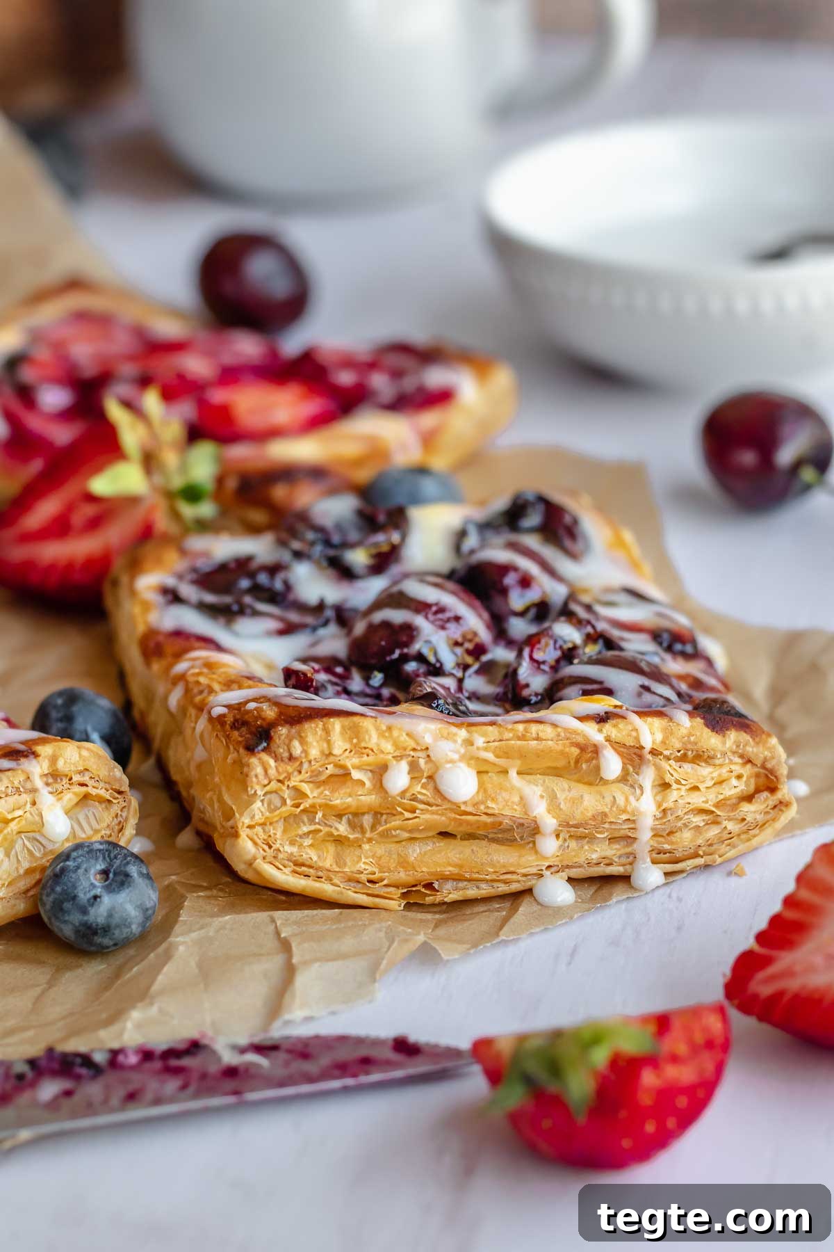 Fruit and Cream Cheese Danish with Flaky Puff Pastry 3 A blueberry cream cheese danish topped with vanilla icing.
