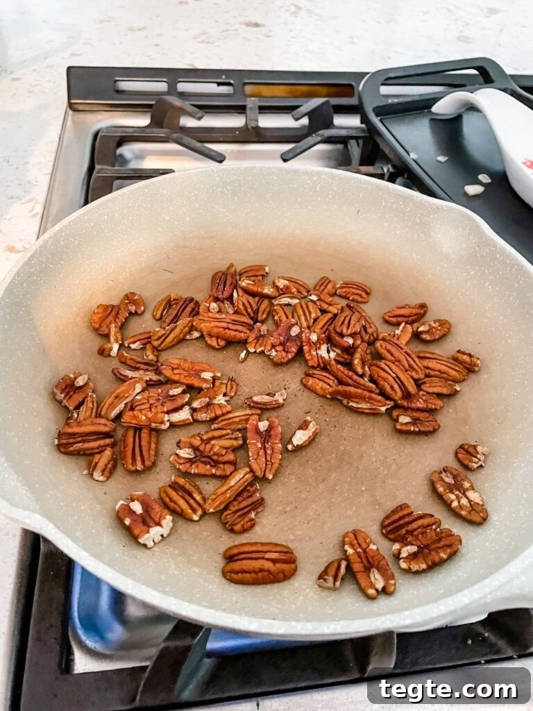 The pecans being lightly toasted in a pan