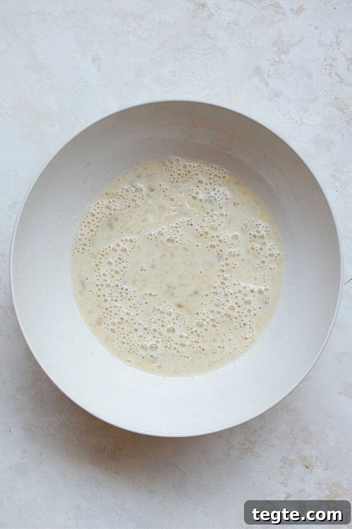 Vegan Baked Oatmeal Recipe for Busy Mornings 4 Mixing mashed banana, flax eggs, plant milk, and vanilla extract in a bowl.