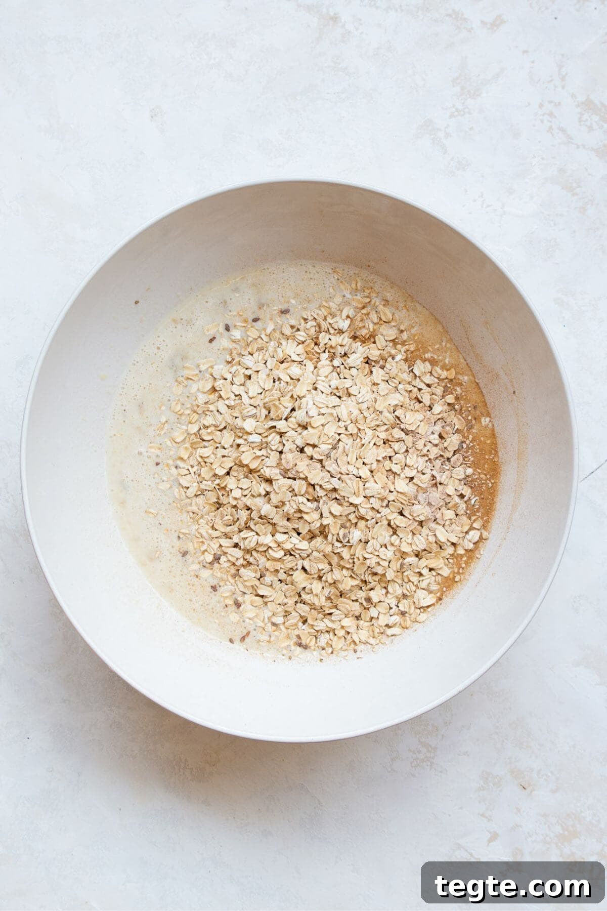 Vegan Baked Oatmeal Recipe for Busy Mornings 5 Adding rolled oats, cinnamon, baking powder, and salt to the wet ingredients bowl.