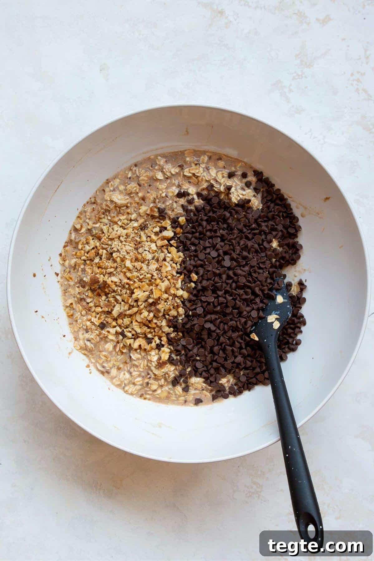 Vegan Baked Oatmeal Recipe for Busy Mornings 6 Adding walnuts and chocolate chips to vegan baked oatmeal batter.