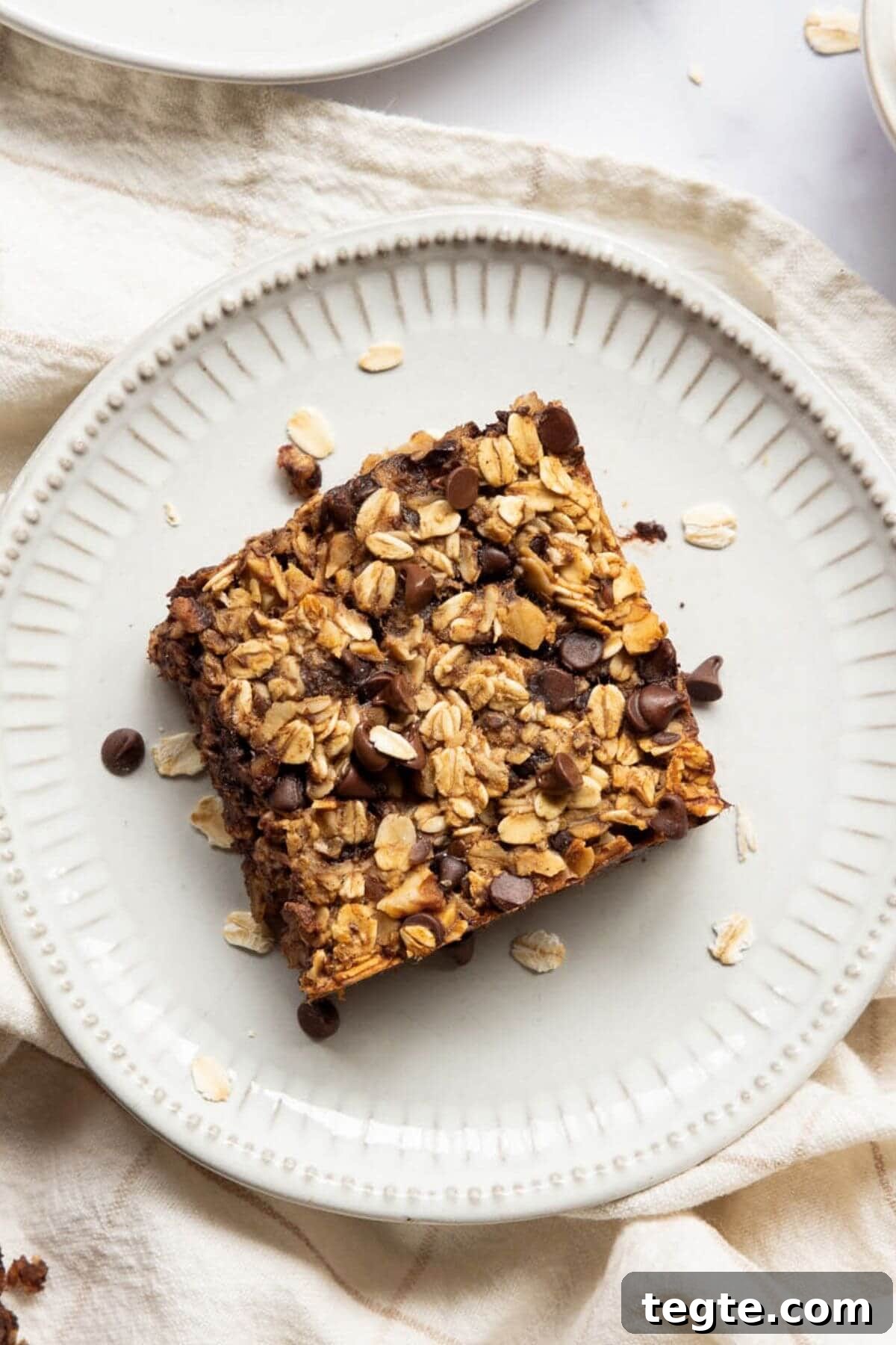 Vegan Baked Oatmeal Recipe for Busy Mornings 9 Soft square of chocolate chip vegan baked oatmeal on a plate.